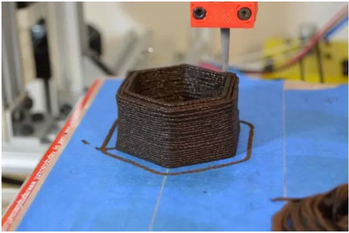 A 3D printer lays down used coffee grounds to make a flower planter