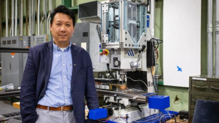 Hang Yu, associate professor of materials science and engineering, with a miniaturized additive friction stir deposition machine used in his advanced manufacturing research. Photo by Peter Means for Virginia Tech.
