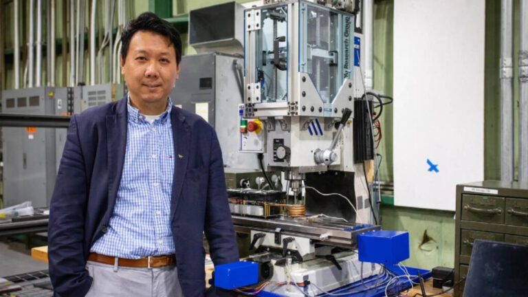 Hang Yu, associate professor of materials science and engineering, with a miniaturized additive friction stir deposition machine used in his advanced manufacturing research. Photo by Peter Means for Virginia Tech.